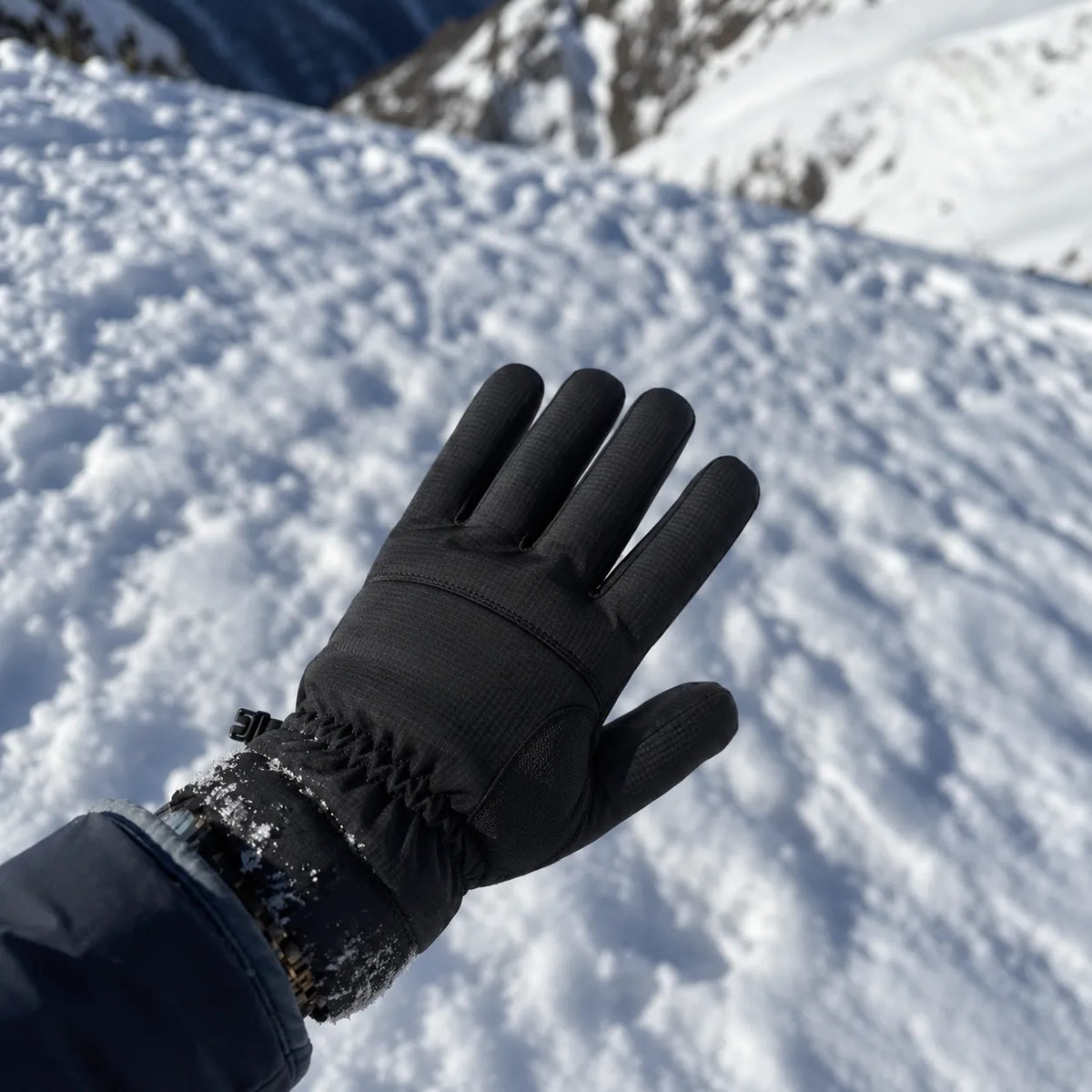 Black glove held above snowy trail